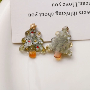 Detail of clear resin Christmas tree charms with gold stars and botanical dried flower inserts