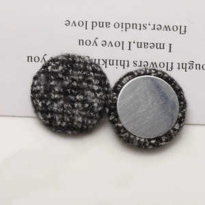 Detailed macro view of black tweed fabric buttons with polished silver metal back for DIY crafts
