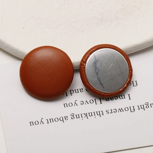 Macro detail of round brown leather button with lychee texture and silver metal base