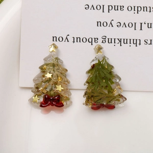 Detailed close-up of resin Christmas tree pendants with gold foil and dried flowers