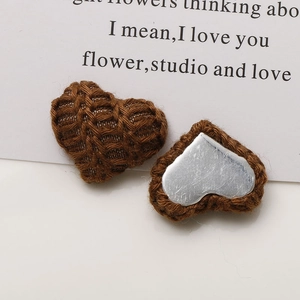 Detail showing knitted heart charm with 3D texture and metallic silver backing for DIY