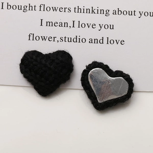 Close-up of black knitted heart charms with silver metal backing for DIY hair accessories