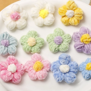 Top view of colorful plush crochet puff flowers on a ceramic plate for DIY crafts