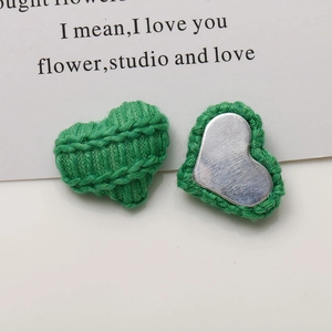 Detailed view of green knitted heart accessories with clear texture and metal base