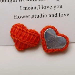 Detail of orange knitted heart-shaped button with a flat silver metal backing for DIY crafts