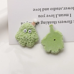 Detailed macro view of green fuzzy monster DIY accessory with pink hat and googly eyes