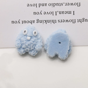 Macro detail of blue fuzzy monster resin charms showing plush texture and center hole