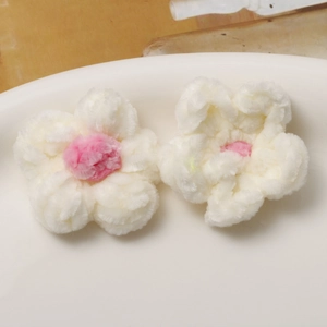 Close-up of handmade white and pink plush puff flower crochet accessories for jewelry