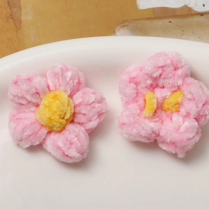 Detailed macro view of handmade plush pink crochet flowers with yellow stamens for DIY crafts