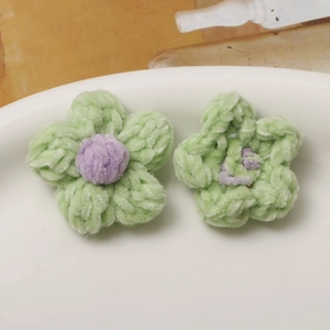 Detail of handmade crochet puff flower accessories in green and purple yarn