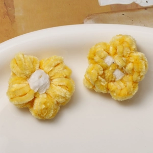 Macro shot of two yellow and white handmade crochet puff flower accessories on ceramic