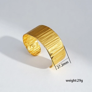 Macro view of gold stainless steel bangle showing 27.2mm width and hammered texture