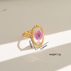 Detailed macro view of gold oval resin ring with purple dried flower and beaded edge