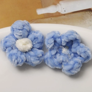 Close-up of handmade crochet puff flowers in soft blue and white chenille yarn
