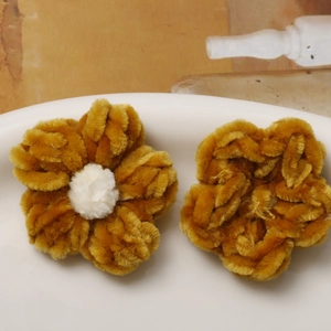 Detailed macro view of handmade yellow plush puff flower DIY accessories in a white tray
