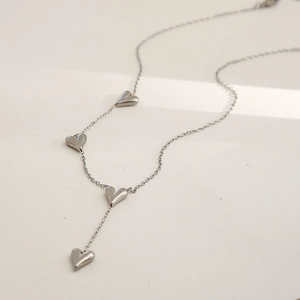 Detailed view of long Y-shaped silver chain necklace with four minimalist 3D heart charms