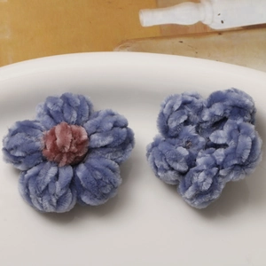 Detail of handmade plush crochet flowers in purple and blue chenille for DIY accessories