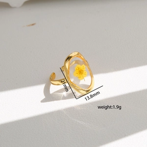 Detail shot of vintage gold-tone ring featuring a yellow dried flower in an oval frame