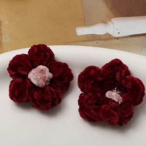 Macro shot of handmade crochet burgundy puff flowers for DIY jewelry and accessories
