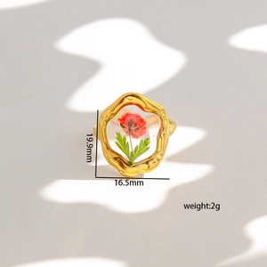 Macro shot of gold ring with real dried red flower and leaf in clear resin dome