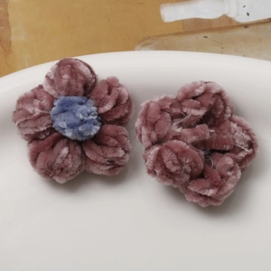 Detail of pink and purple crochet puff flowers with soft velvet texture on a white plate