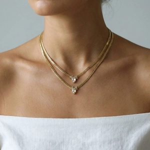Double-layered gold snake chain necklace featuring marquise-cut zircon pendants worn on neck