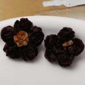 Macro detail of two dark brown plush crochet flower accessories for DIY crafts and jewelry