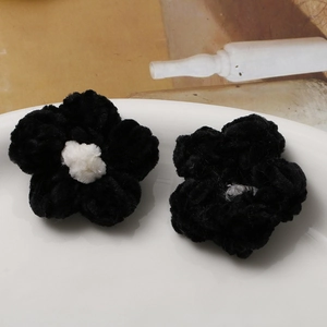 Detail of handmade plush crochet black puff flowers with white centers for accessories