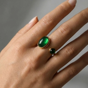Anillo vintage ajustable en oro con dos piedras verde esmeralda en la mano de una modelo