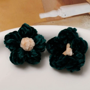 Macro detail of handmade crochet puffy flowers in dark green and cream chenille yarn