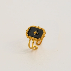 Vue macro d'une bague dorée ajustable avec émail noir et motif étoile en relief