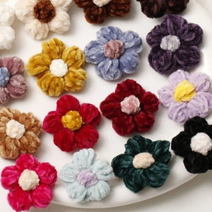 Handmade crochet puff flowers in assorted colors displayed on a white ceramic plate