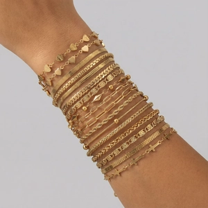 Ensemble de bracelets dorés superposés avec pendentifs cœur et divers styles de chaînes