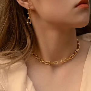 Macro detail of luxury gold-plated U-link chain necklace and matching earrings on model