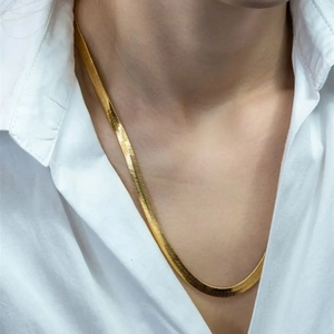 Detailed view of a minimalist gold stainless steel snake bone necklace on a model.