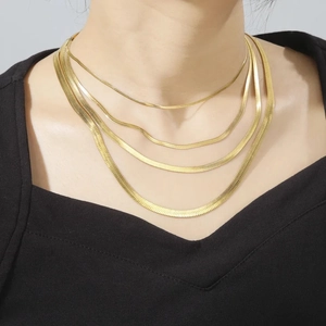 Layered minimalist gold stainless steel snake bone necklaces on a female model wearing black
