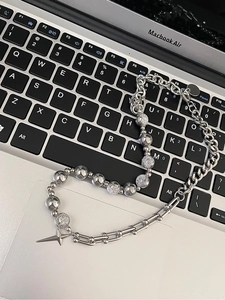 Detail of silver star pendant on mixed link chain necklace over a laptop keyboard