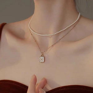 Double-layered gold titanium steel necklace featuring small pearls and a letter H pendant