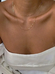 Primer plano de collar de doble cadena de serpiente dorada en el cuello de modelo