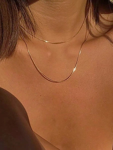 Primer plano de collar de doble capa con cadena de serpiente dorada puesto en mujer