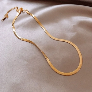 Detail of flat golden herringbone chain with lobster clasp on luxury silk background