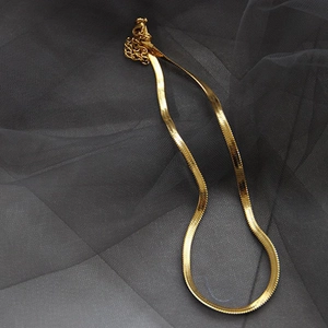 Detail of gold-plated flat snake chain featuring a polished mirror finish and lobster clasp