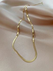 Detailed shot of golden herringbone snake chain on luxury satin with lobster clasp closure
