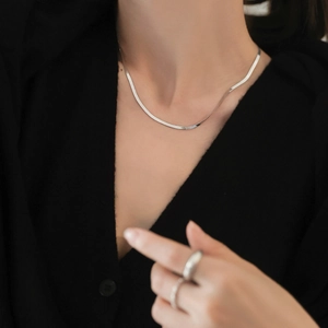 Double layered silver herringbone snake chain necklace on model with matching rings