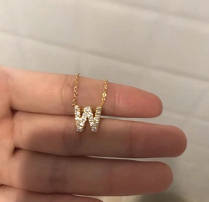 Dettaglio collana in acciaio al titanio placcato oro 18K con ciondolo a lettera W e zirconi