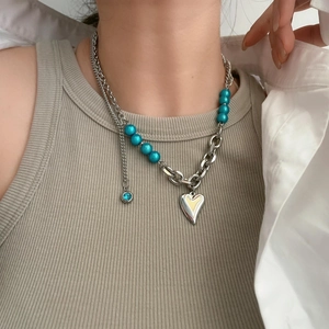 Layered silver necklace with blue pearls and heart pendant on a female model