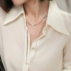 Polished silver double-layered snake bone chain necklace worn with a white shirt