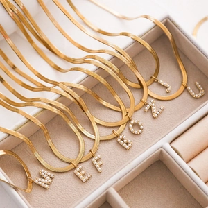 Goldene flache Schlangenkette mit Perlen besetzten Buchstabenanhängern im Retro-Stil