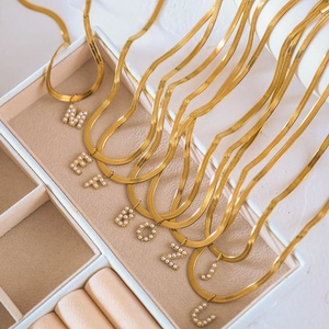 Detail der goldenen Schlangenkette mit Großbuchstaben aus weißen Perlen besetzt