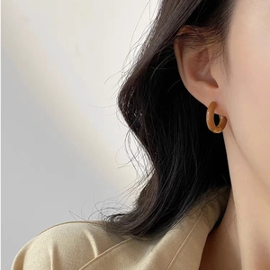 Close-up of vintage brown amber resin hoop earring worn by model in a soft lighting